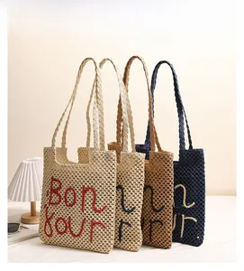 Detail view of woven straw shoulder bags with Bonjour embroidery in four stylish colors
