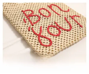 Detail of hollow woven straw bag with red Bon Jour embroidery for summer beach