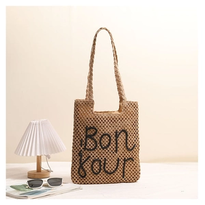 Detailed view of Bonjour embroidered straw tote with hollow mesh weave and long handles