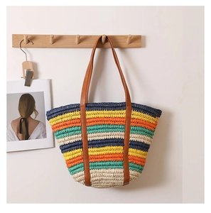 Detailed view of colorful striped woven tote bag with brown leather handles hanging on wall