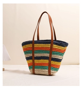 Detail of colorful striped straw tote bag with brown faux leather straps for beach vacation