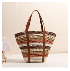 Close-up of a striped straw tote bag with brown leather handles in a home setting