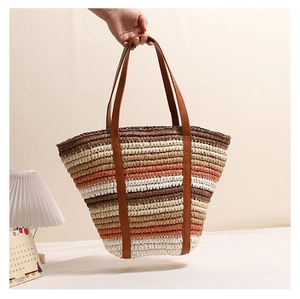 Detail of colorful striped straw tote bag showing hand-woven texture and leather handles