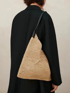 Detail of minimalist straw tote with geometric shape and contrasting black leather strap