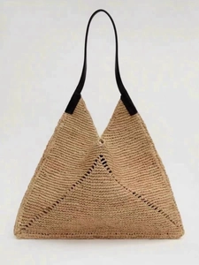 Detail of hollow woven raffia triangle bag with sleek black leather shoulder straps