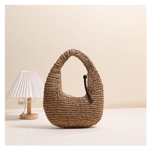 Close-up of woven straw hobo bag featuring natural texture and black rope knot detail
