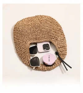 Detail showing inner capacity of straw bag with phone, sunglasses and cosmetics inside