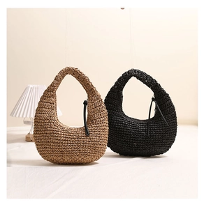 Detail of hand-woven straw hobo bags in tan and black colors with fringe accents