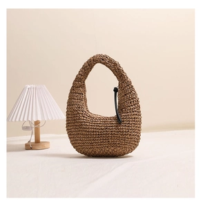 Detail of hand-woven straw hobo bag with black leather fringe tassel on fabric surface