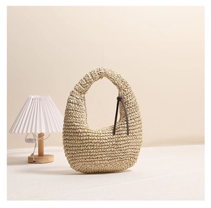 Detailed close-up of handmade beige woven handbag showing dense texture and tassel detail