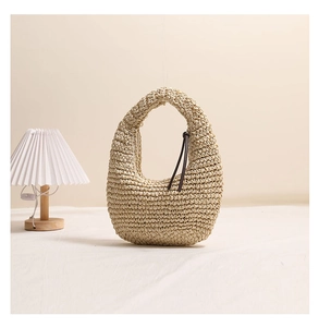 Detail of a beige crescent straw handbag with woven texture and brown cord accents