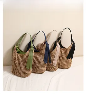 Détail des sacs seau en paille tressée avec de longs rubans décoratifs en quatre couleurs