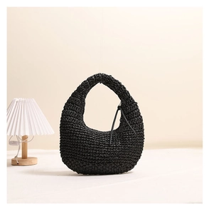 Detail of black woven hobo straw bag featuring a minimalist tassel and textured finish