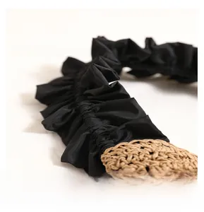 Macro shot of stylish black ruffled fabric and natural woven straw detail on a handbag