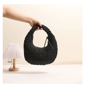 Detail of black crochet straw tote featuring a leather tassel and woven handle