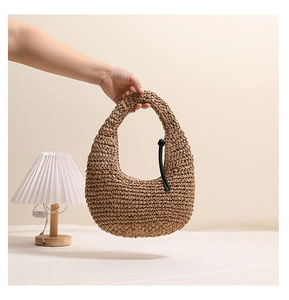 Detail of crescent straw handbag with black tassel charm for beach vacation fashion
