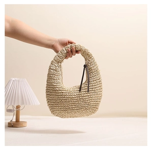 Detail of hand-woven straw bag with hobo silhouette and brown leather accents