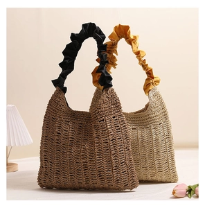 Detail of woven straw tote bags with ruffled handles in brown and beige colors