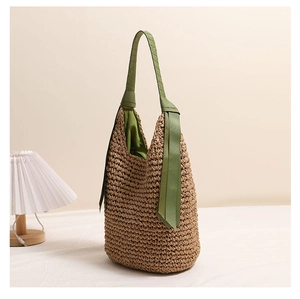 Gros plan sur la texture tissée et le ruban en tissu vert du sac à bandoulière en paille brun