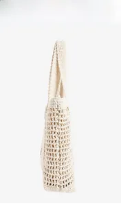 Detail of hollow mesh crochet pattern on cream cotton woven shoulder beach bag