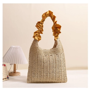 Detailed view of woven straw beach bag with elegant yellow ruffled fabric handle