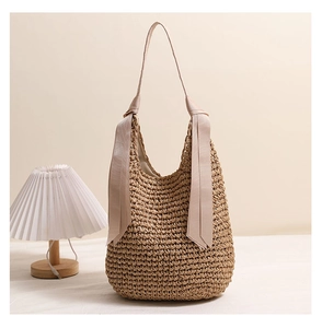 Gros plan du sac bandoulière en paille tressée avec ruban en satin beige élégant