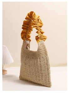 Detailed macro view of yellow ruffled edge and straw woven texture on a summer tote bag