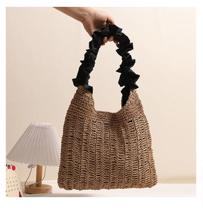 Detailed shot of brown woven straw bag featuring contrast black pleated ruffle handle