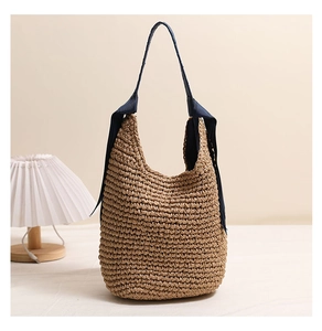 Détail du sac à bandoulière en paille tressé avec motif en spirale et ruban bleu souple