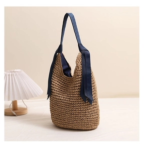 Détail du sac à bandoulière en paille avec ruban bleu foncé élégant et nœud décoratif