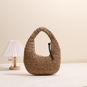 Handmade woven straw tote bag with black leather tassel detail for summer beach vacation