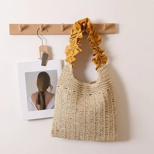 Straw tote bag with yellow ruffled shoulder strap and beige hollow weave for beach vacation