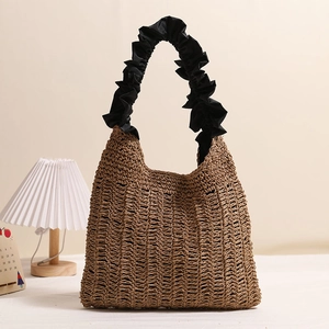 Handwoven straw tote bag with black ruffled handles for summer beach vacations