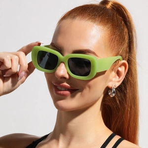 Close-up of vintage thick-frame rectangle sunglasses in light green on a fashion model