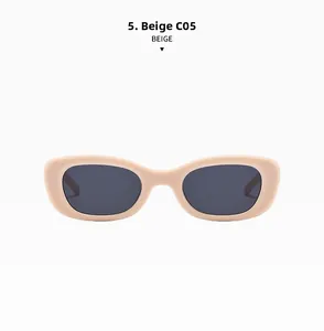 Détail de lunettes de soleil ovales beige avec verres gris et charnières métalliques