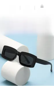 Close-up of black rectangular sunglasses with wide temples on a minimalist display