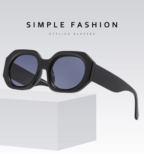 Close-up of geometric black frame sunglasses with blue lenses on a white display pedestal