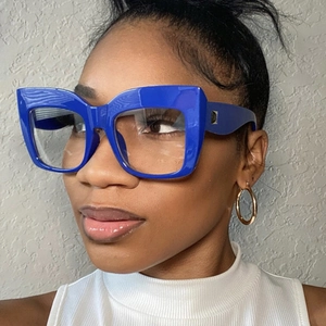 Detail of oversized royal blue square glasses frame worn by a model in a profile view
