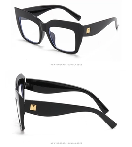 Detail view of oversized black cat-eye glasses frame with golden square decorative hinges