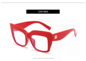 Detail of red oversized square glasses frame with golden metal hinge and blue light lenses