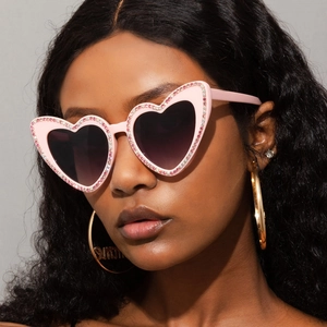 Gros plan de lunettes de soleil cœur rose avec strass et grandes boucles d'oreilles été