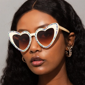 Détail des lunettes de soleil coeur crème avec strass bleus et blancs sur modèle