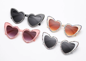 Détail de lunettes de soleil en forme de cœur en quatre couleurs avec monture en strass