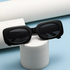 Fashionable square black sunglasses with thick frames on a minimalist white stand