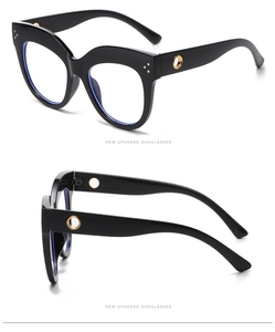 Macro view of oversized black cat-eye glasses frame with gold hinge and silver rivets