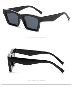 Detail view of glossy rectangular black sunglasses with thick frames and grey lenses