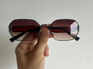 Detail view of small frame sunglasses with dark tea gradient lenses and metal frame
