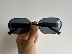 Detail view of dark grey octagonal lenses with sleek black metal frames for sunglasses