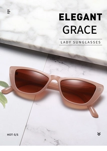 Detail of trendy nude cat-eye sunglasses with brown lenses on white marble surface