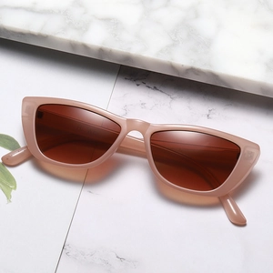 Fashionable cat-eye sunglasses with translucent pink frame and dark brown lenses on marble